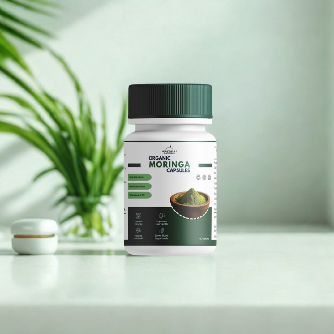 Bottle of Moringa capsules on a white surface with a plant in the background