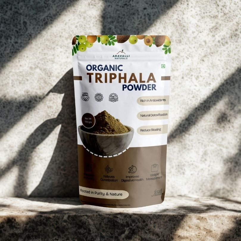 Package of Aravalli Organics Organic Triphala Powder on a textured stone surface